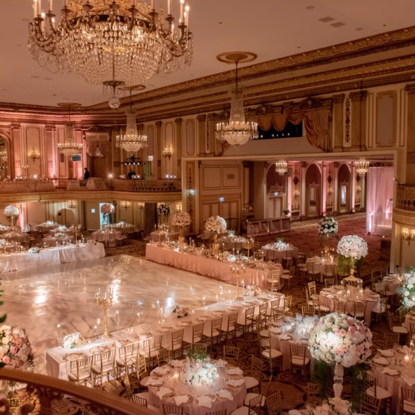 Elegant ballroom wedding reception with crystal chandeliers, white floral centerpieces, and gold chiavari chairs designed by luxury event designer Erin McDonald