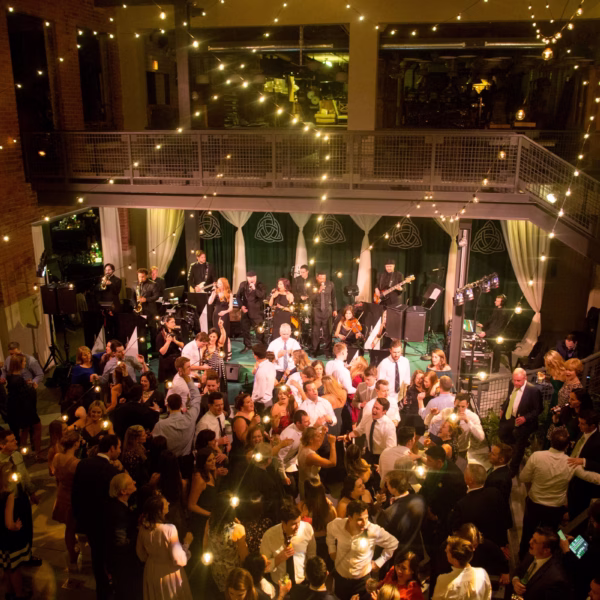 Luxury wedding reception with live band performance and guests dancing in elegant venue with string lights overhead in Chicago