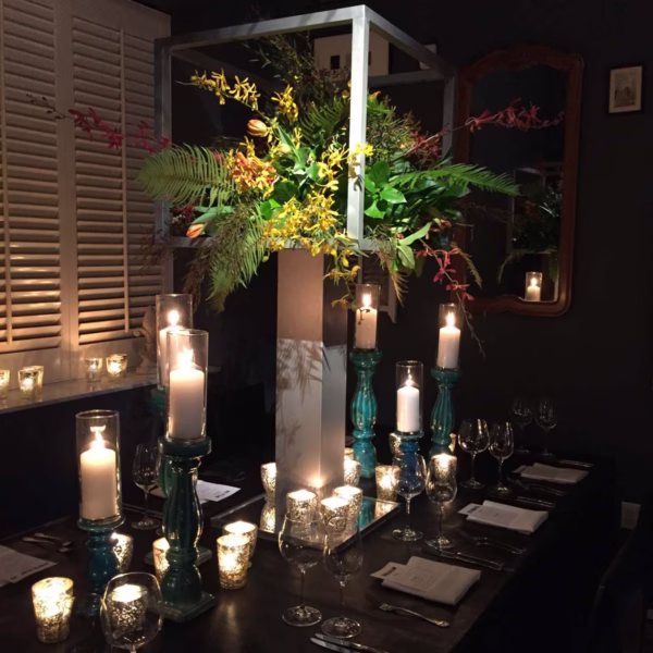 Elegant candlelit wedding tablescape with lush greenery centerpiece and modern geometric frame designed by Erin McDonald