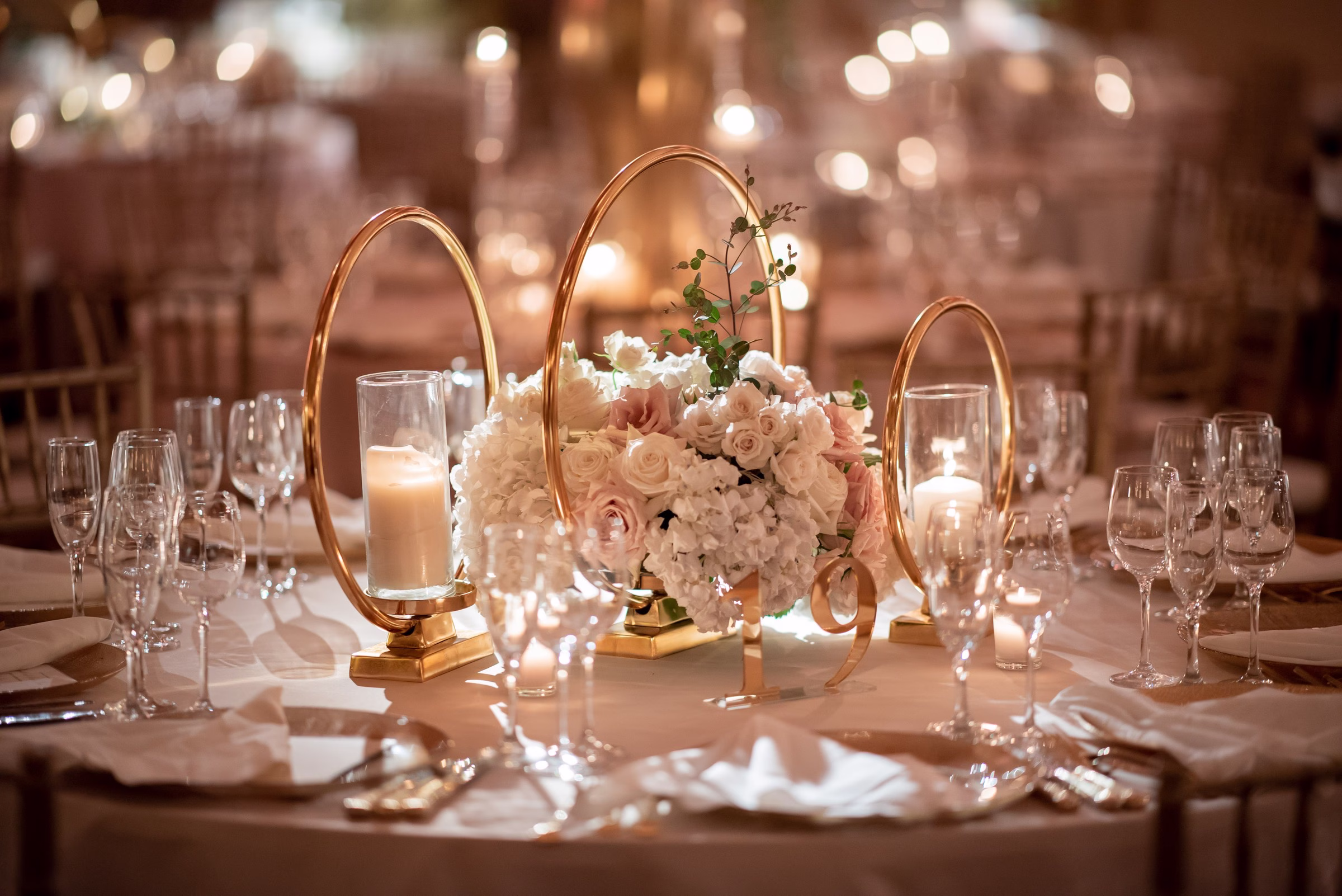 Elegant wedding reception centerpiece with blush roses, white hydrangeas and gold geometric candle holders designed by Erin McDonald for Chicago and Rochester NY weddings