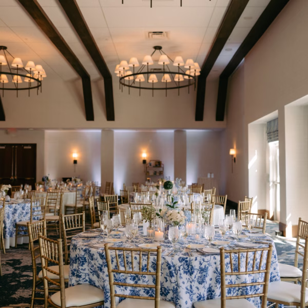 Elegant Chicago wedding reception with blue and white floral linens, gold chiavari chairs, and dramatic chandeliers designed by Erin McDonald