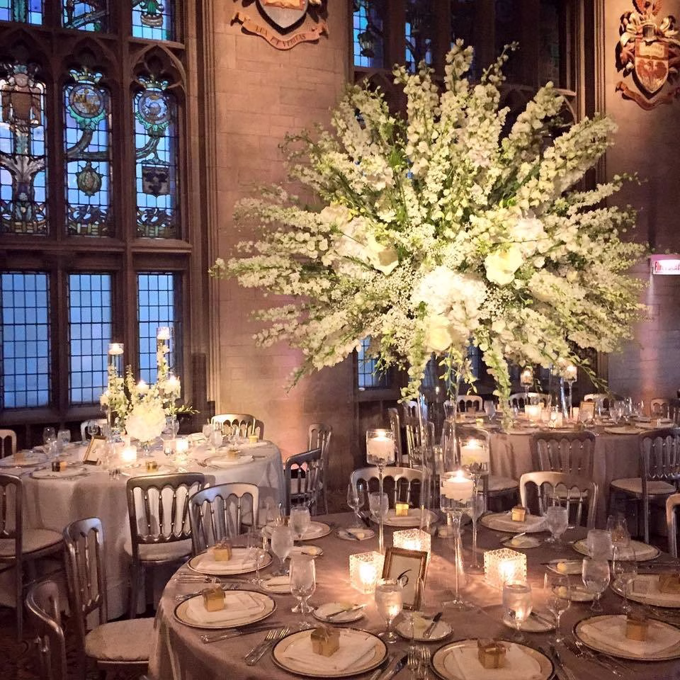 Elegant white floral centerpieces and candlelit tables designed by Chicago wedding designer Erin McDonald in gothic ballroom venue
