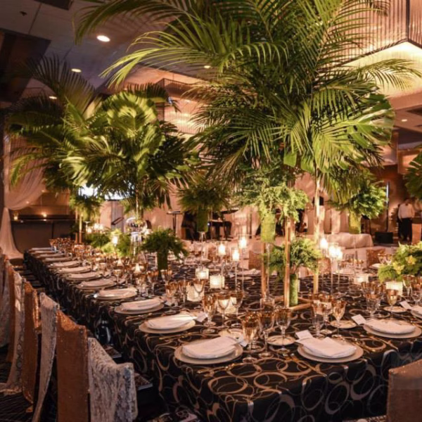 Elegant wedding reception tablescape with tall tropical palm centerpieces and formal place settings designed by Chicago wedding designer Erin McDonald