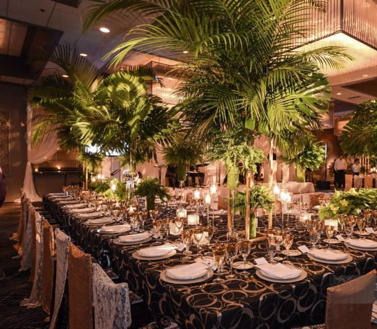Elegant wedding reception tablescape with tall tropical palm centerpieces and formal place settings designed by Chicago wedding designer Erin McDonald