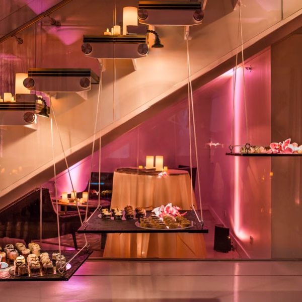 Modern wedding dessert display with suspended floating shelves under contemporary staircase with pink uplighting in Chicago