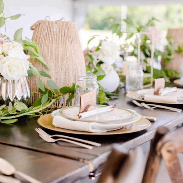 Elegant wedding tablescape with white florals, woven lampshade centerpiece, and neutral place settings designed by Erin McDonald