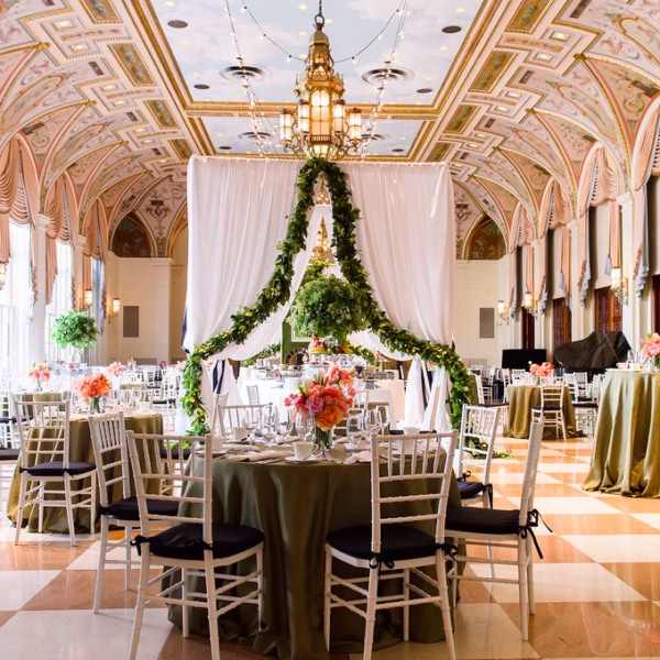 Elegant ballroom wedding reception with ornate ceiling, green linens, coral florals, and draped ceremony backdrop designed by Chicago wedding planner Erin McDonald