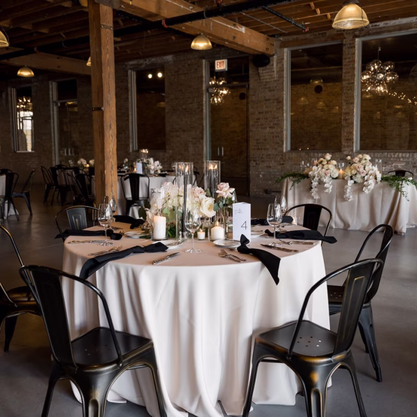 Elegant industrial wedding reception table setting with black chairs and white linens designed by Chicago wedding planner Erin McDonald