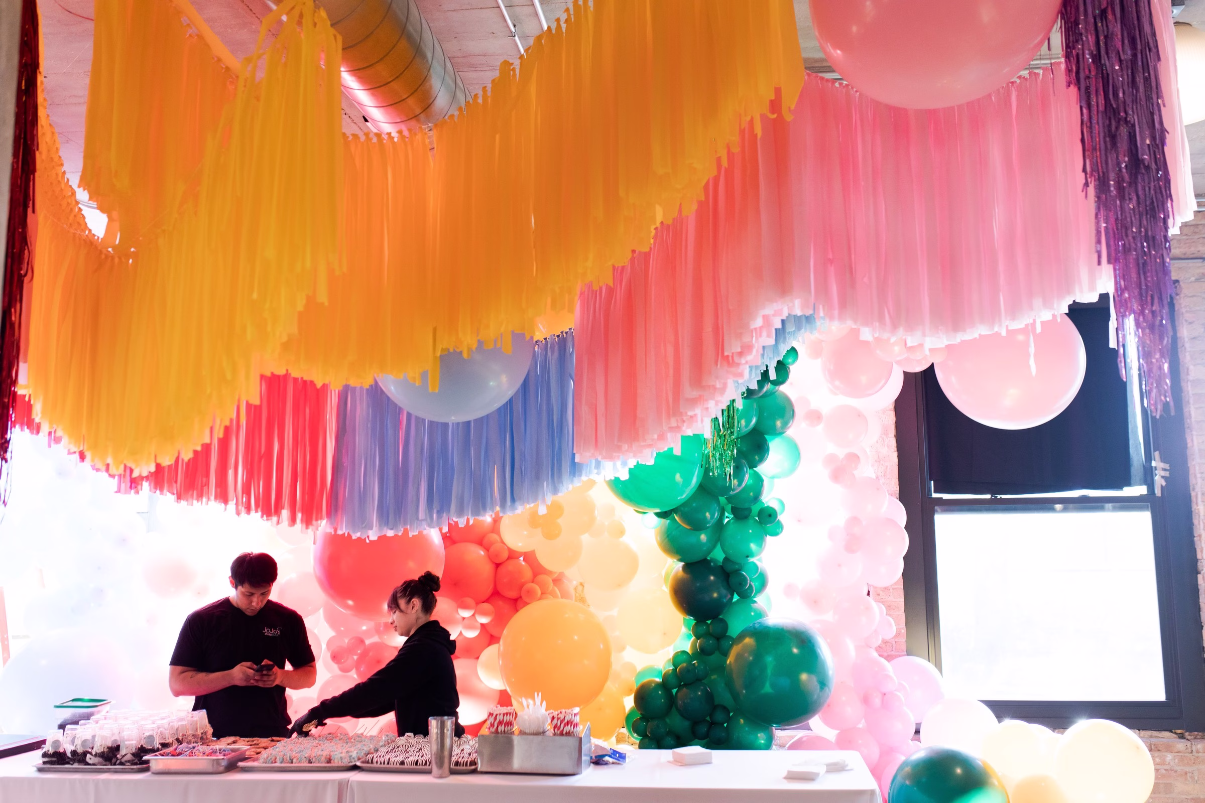 Vibrant colorful balloon installation and fringe backdrop