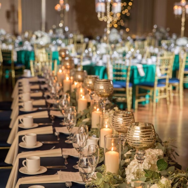 Sophisticated navy and gold wedding reception tablescape with metallic candle holders, white pillar candles, and eucalyptus garland designed by Erin McDonald