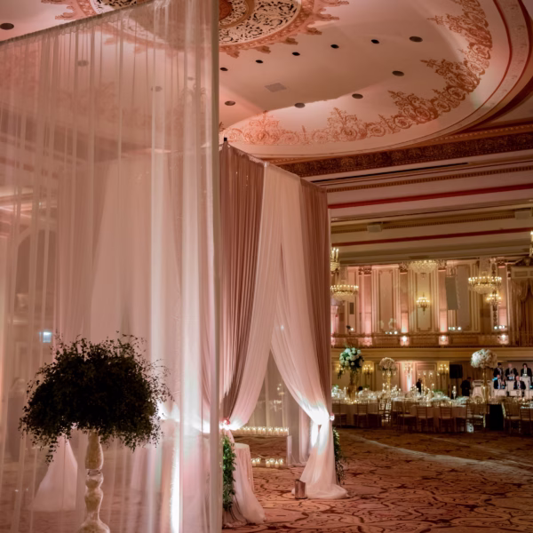 Elegant white fabric draping and floral arrangements create a romantic ceremony space designed by Erin McDonald