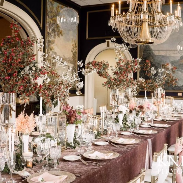 Elegant wedding reception tablescape with tall floral centerpieces, crystal chandelier, and blush linens designed by Chicago wedding designer Erin McDonald