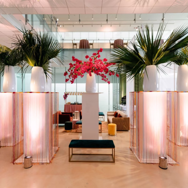 Elegant pink fringe ceremony arch with tropical palm arrangements and red bougainvillea designed by Erin McDonald
