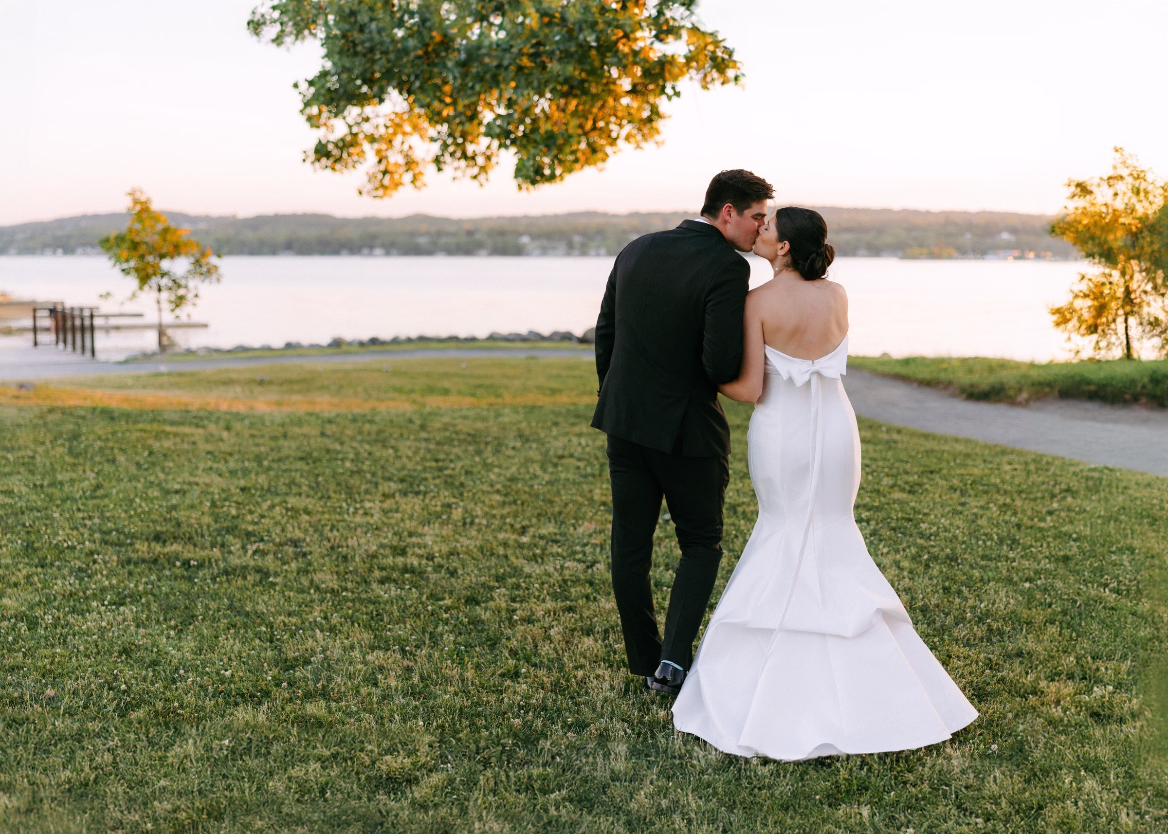 rochester ny wedding planning lakeside sunset couple portrait - Destination Event Design Bride and groom embrace during golden hour sunset at lakeside Rochester NY wedding venue coordinated by wedding designer Erin McDonald