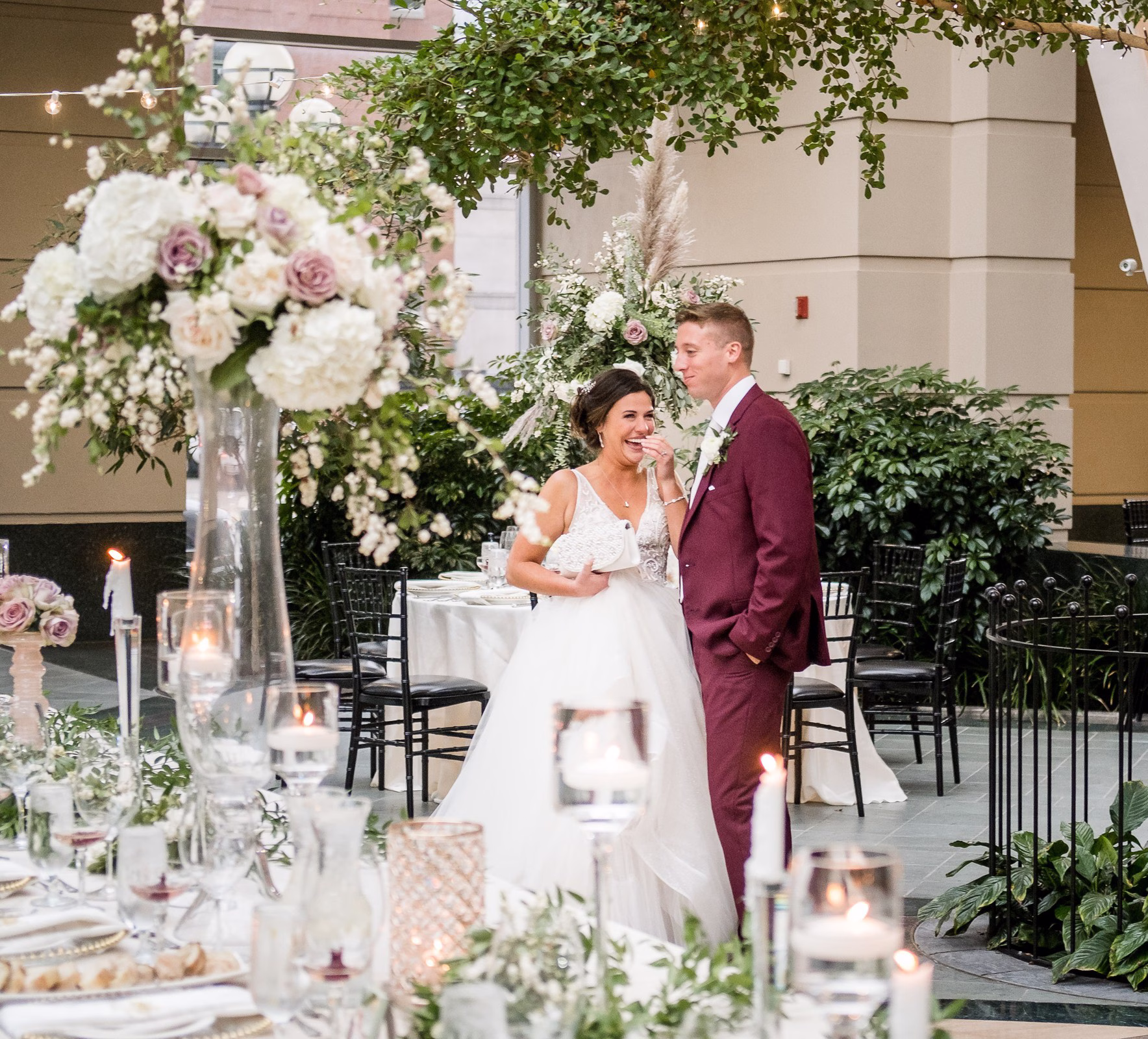 Wedding designer Erin McDonald creates elegant reception decor with white and blush floral arrangements, candles, and greenery for romantic celebration