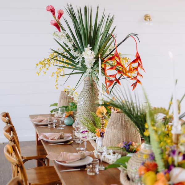Tropical wedding tablescape with woven basket centerpieces and vibrant florals designed by Erin McDonald